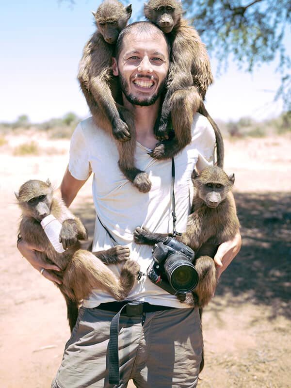 namibia-man-with-camera-holding-four-baby-baboons-YKXWTT5f.jpg